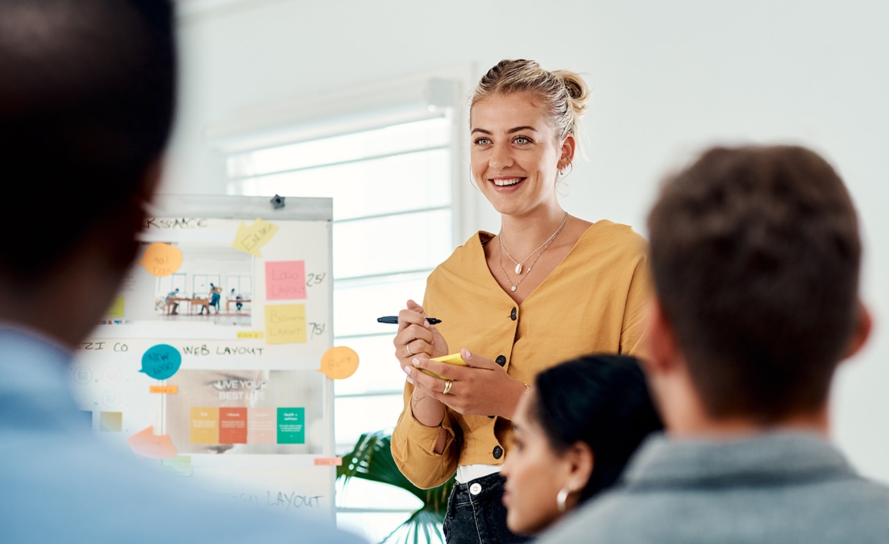 Kvinna leder workshop med postit lapp och penna i handen Kvinna leder workshop med postit lapp och penna i handen