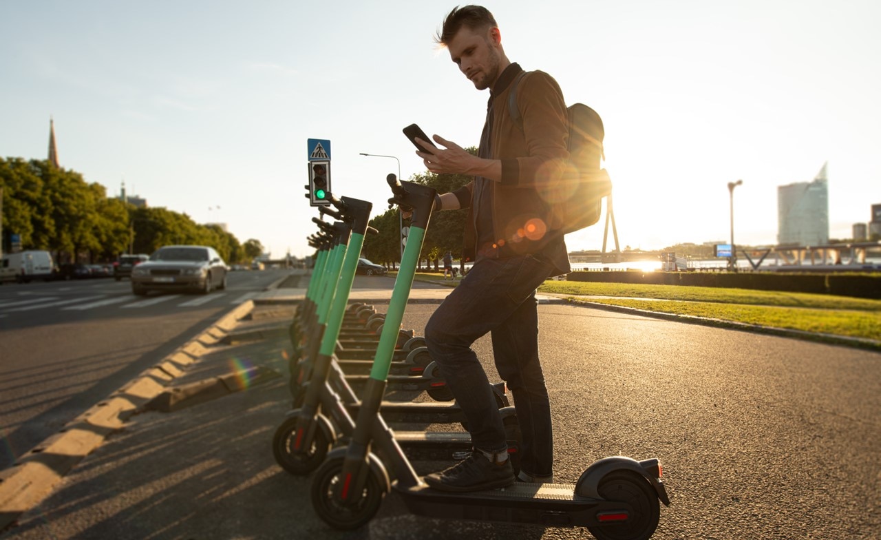 Un homme déverrouille un scooter électrique à l'aide d'un téléphone portable Un homme déverrouille un scooter électrique à l'aide d'un téléphone portable