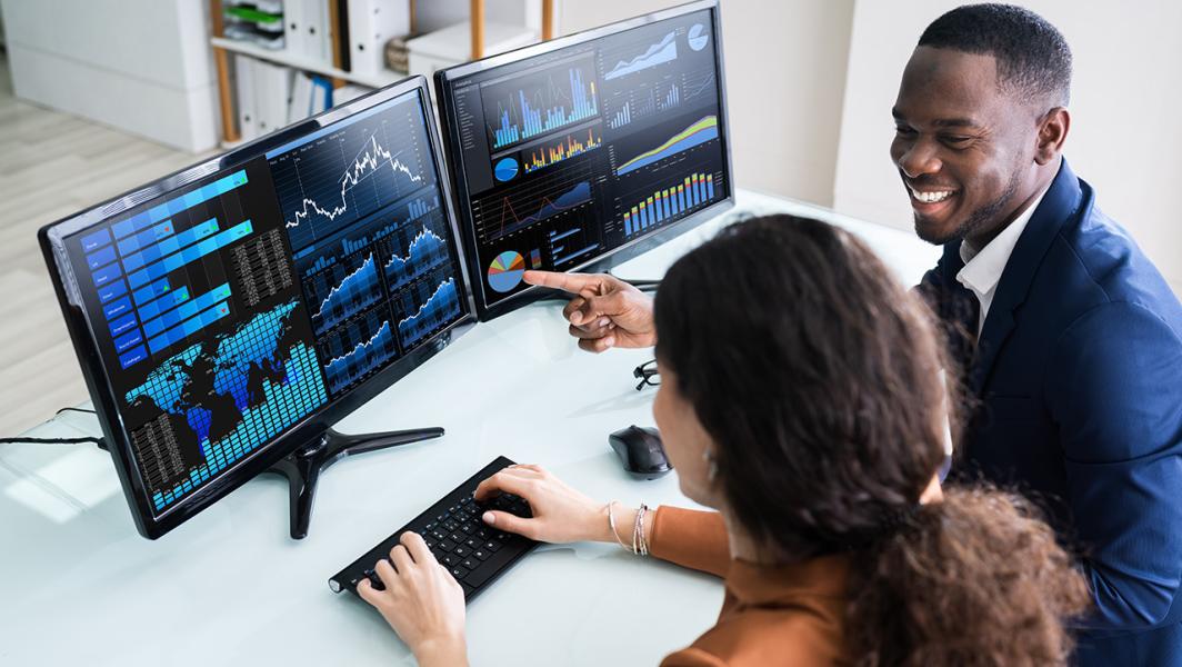Two consultants looking at data together on 2 monitors Two consultants looking at data together on 2 monitors