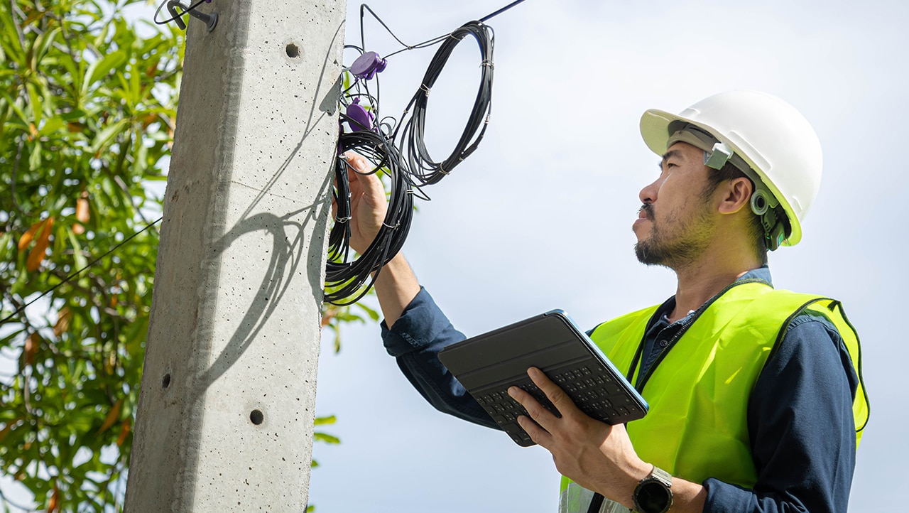 Utilities worker looking at electricity pole Utilities worker looking at electricity pole