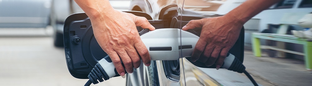 Nahaufnahme einer Person, die ein Elektroauto auflädt Nahaufnahme einer Person, die ein Elektroauto auflädt