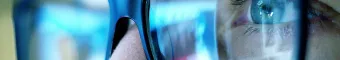 reflection of monitors in glasses of cybersecurity analyst