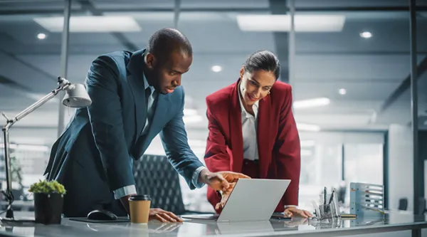 two professionals collaborating in front of a computer together