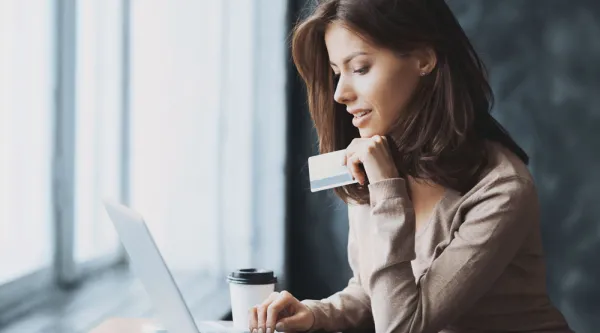 Woman using a card to pay online with a laptop computer