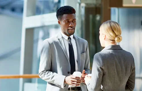 two executives conversing in an office building hallway