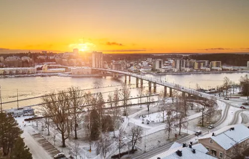Vue aérienne de Joensuu (Finlande) couverte de neige avec le soleil se levant à l’horizon.