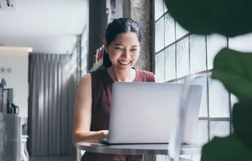 Kvinna arbetar på en dator och ler. 