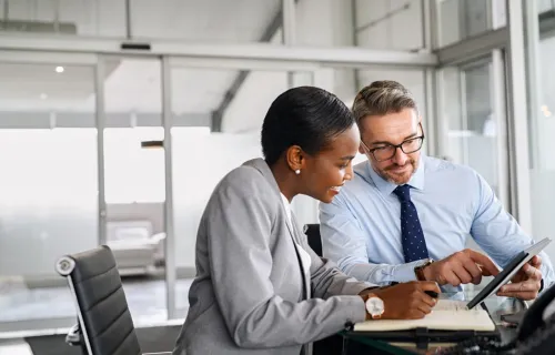 A business woman and business man review data on a tablet