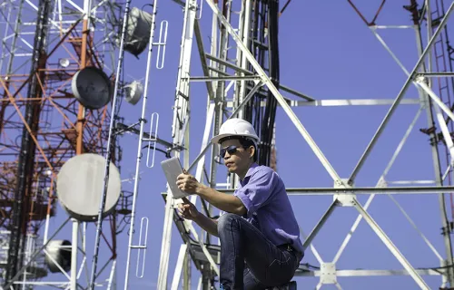 A worker uses technology on communications equipment, representing the CGICarnotsatCarnotSat .solution