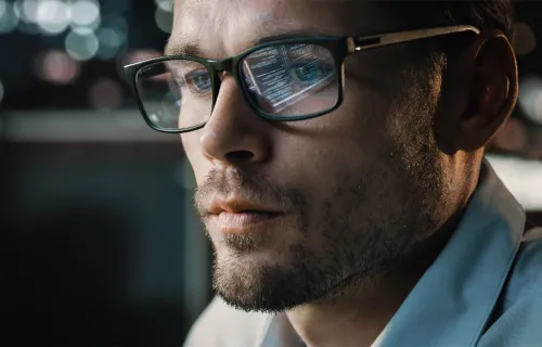 Développeur avec écran d'ordinateur logiciel reflété dans ses lunettes