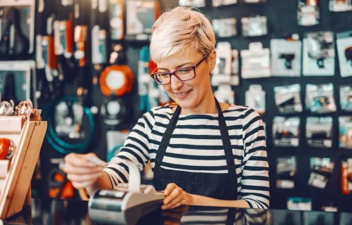 female worker short blonde hair using cash register in bicycle store