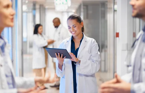 A health professional in a white coat using a tablet