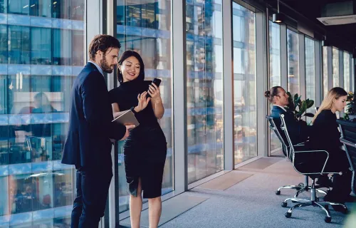 Deux consultants en affaires souriant en regardant un téléphone portable