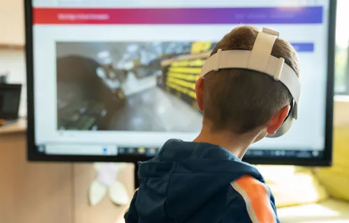 Kind mit VR Brille vor einem Monitor sitzend