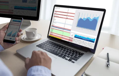 A person using a computer and phone to review data