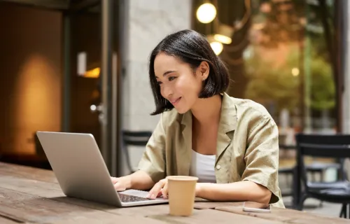 Junge Frau sitzt in einem Café und arbeitet an ihrem Laptop