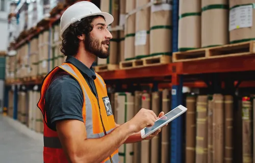 Logistiker steht im Lager und hält einen Tablet in der Hand