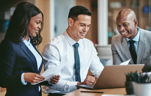 Three people looking at laptop working