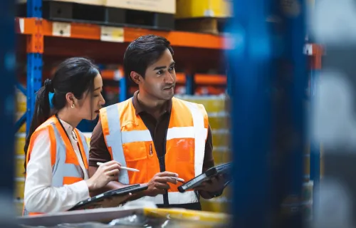 A warehouse worker and manager check stock and inventory using a digital tablet in a retail…