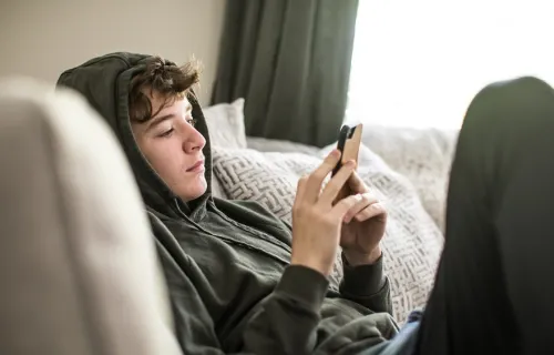 Jeune garçon portant un sweat à capuche et utilisant un téléphone portable