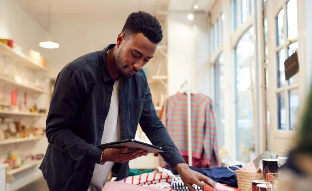 Man selecting T.shirts looking at the online shopping in his tablet