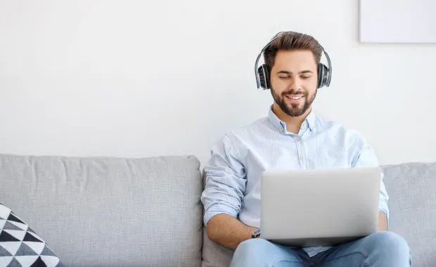 Homme avec des écouteurs qui regarde son ordinateur