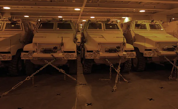 A row of military trucks secured on an aircraft carrier
