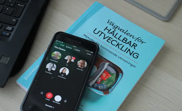 Mobiltelefon som ligger på en bok visar deltagarna på ett teamsmöte
