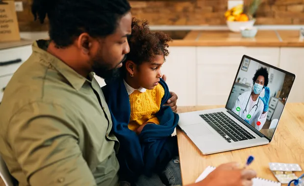 Father and son talking to doctor on computer