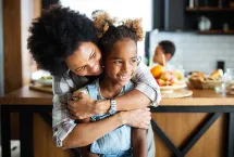 Mother and daughter hugging in the kitchen