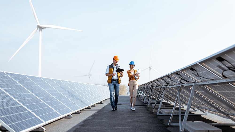 two field utilities workers walking through solar panels